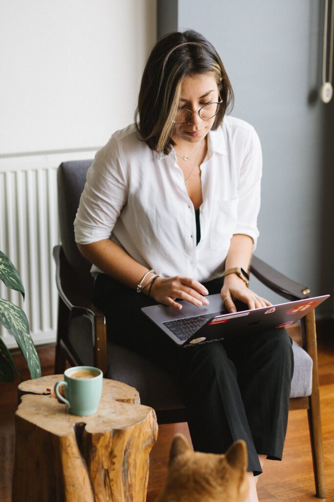 Concentrated woman browsing laptop in living room near dog